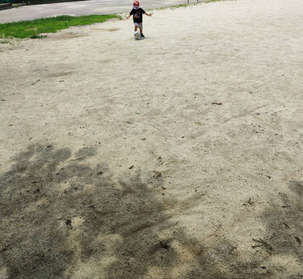 男の子が公園でサッカーをしている様子