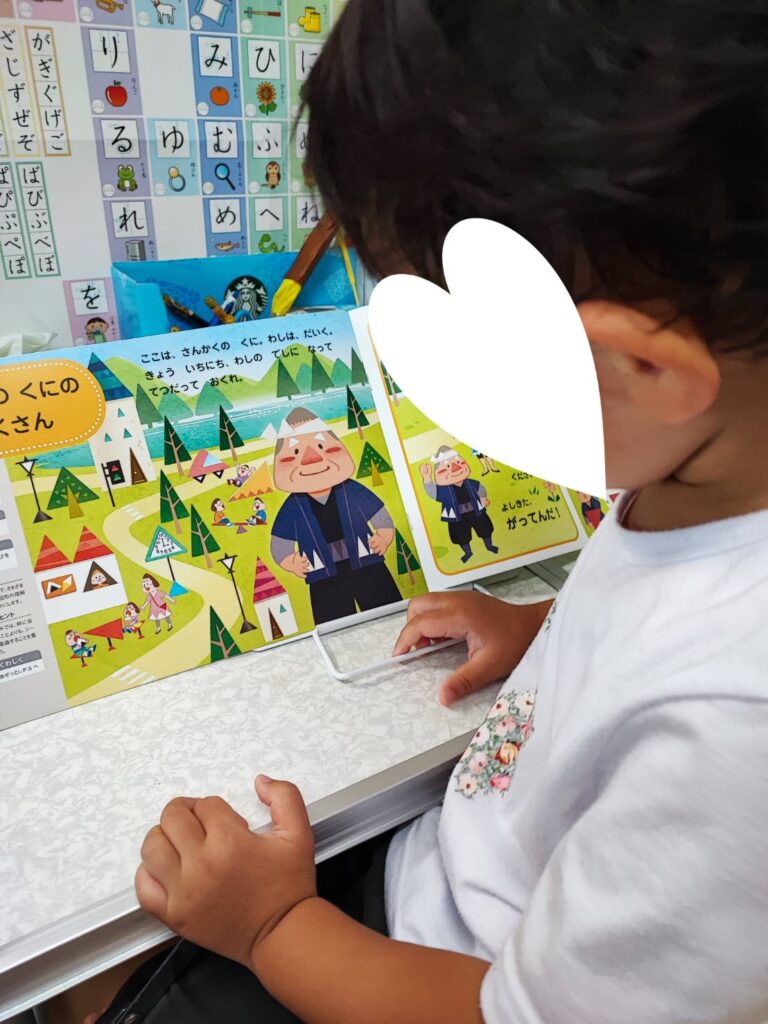 Z会幼児コース年少ぺあぜっと8月さんかくのくにのだいくさんのページを読んでいる様子