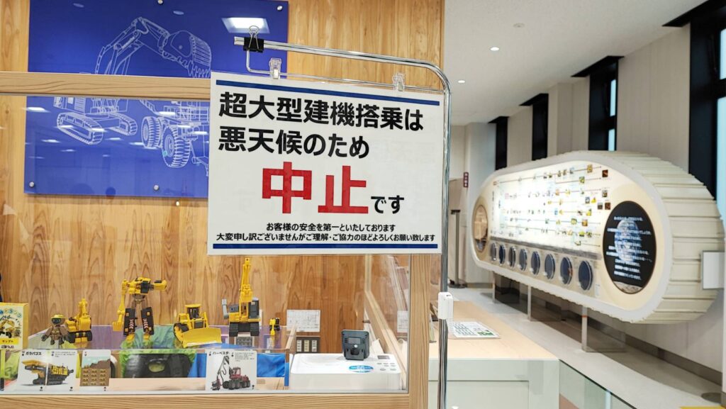 「超大型建機搭乗は悪天候のため中止です」と書かれた看板